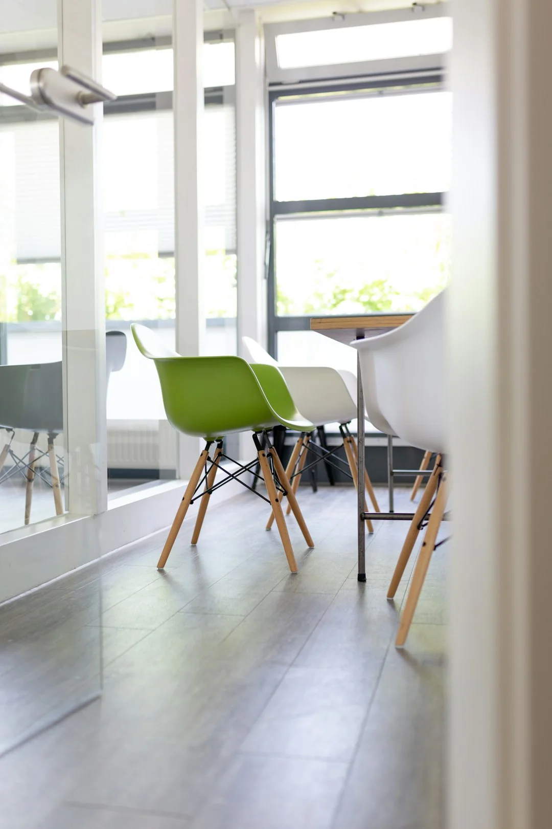 A person raising a couch in a minimalist living room with wooden floors.